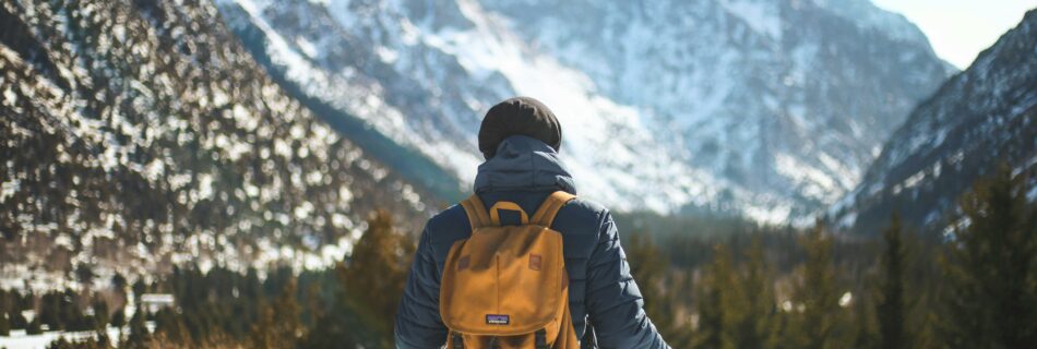 Randonneur en balade hivernale dans le Queyras avec sac &agrave; dos et montagnes enneig&eacute;es